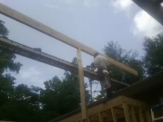 Carpenter setting a ridge beam over a new addition frame — Ice Dam Removal by Roofing Brothers in Spring Hope