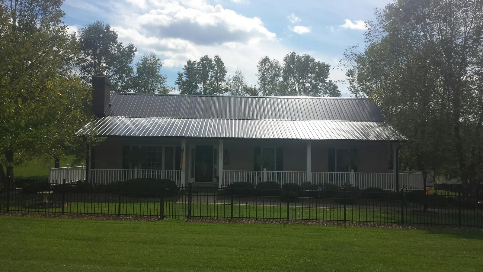 Gray metal roof on a brick ranch with a full width front porch — Gutter Guard Installation work by our crew in Spring Hope