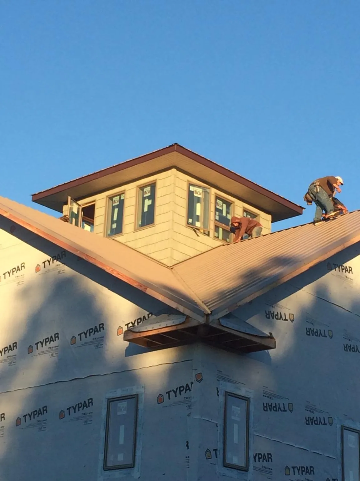 Roofers working around a rooftop cupola on a new metal roof at sunset — Roof Waterproofing in Spring Hope by Roofing Brothers